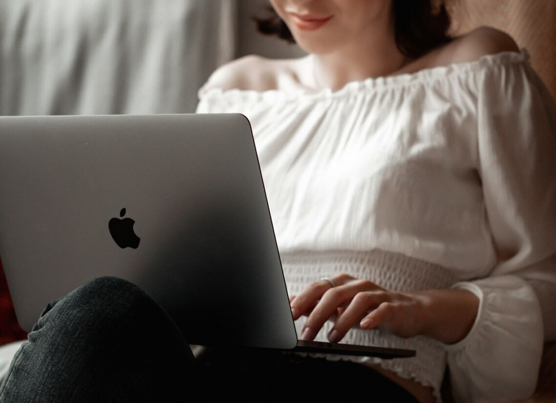 Person in a white off-shoulder top using a MacBook laptop, with text overlay 'What's new in digital?' and the fabrica® logo in the top corner.